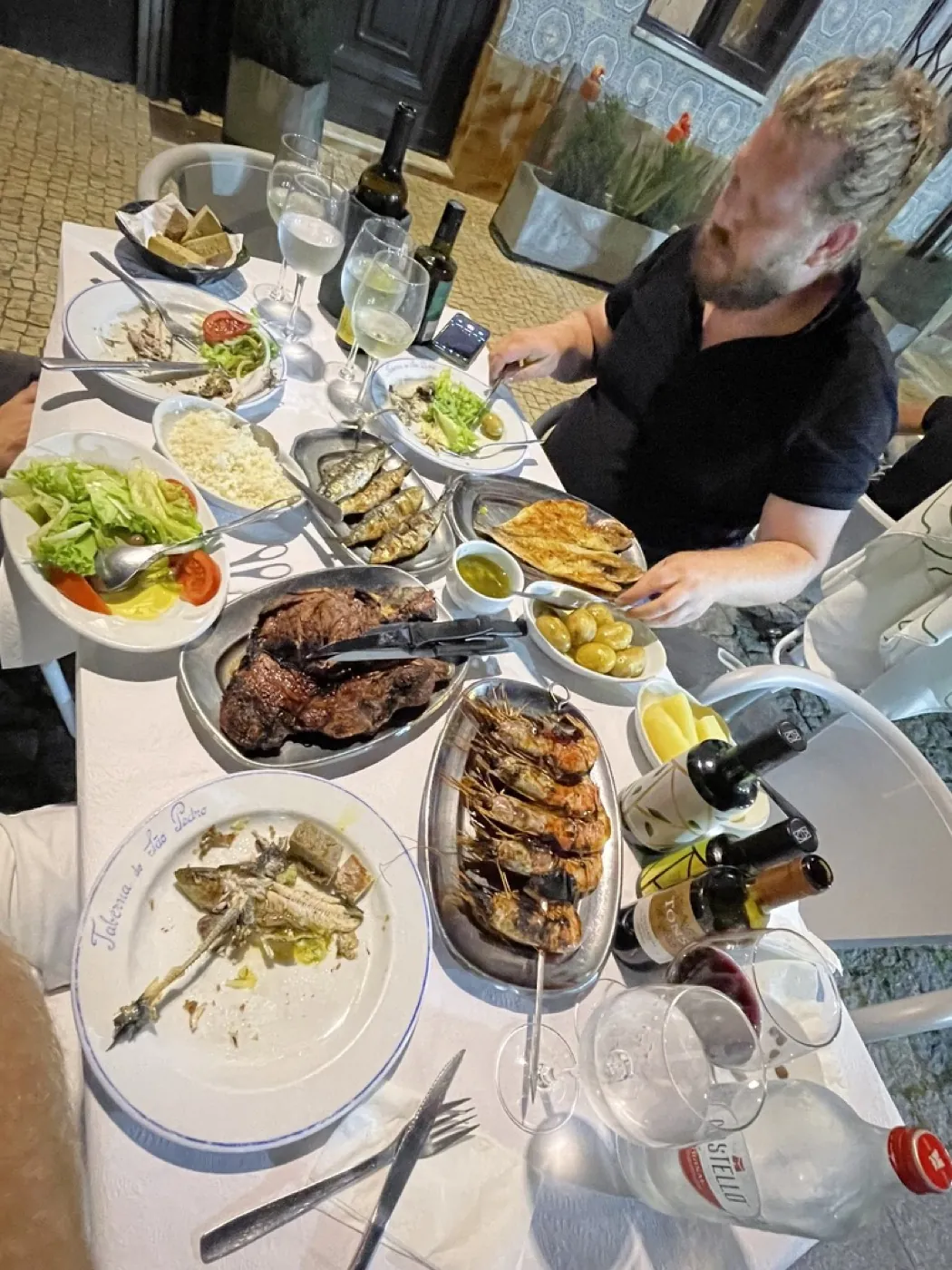An overhead view of a table at Taberna São Pedro in Afurada, loaded with grilled fish, prawns, steak, rice, salad and olives