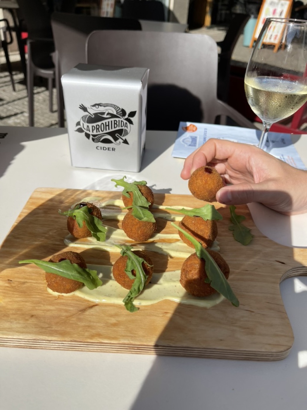 A wooden board of croquettes with salad garnish