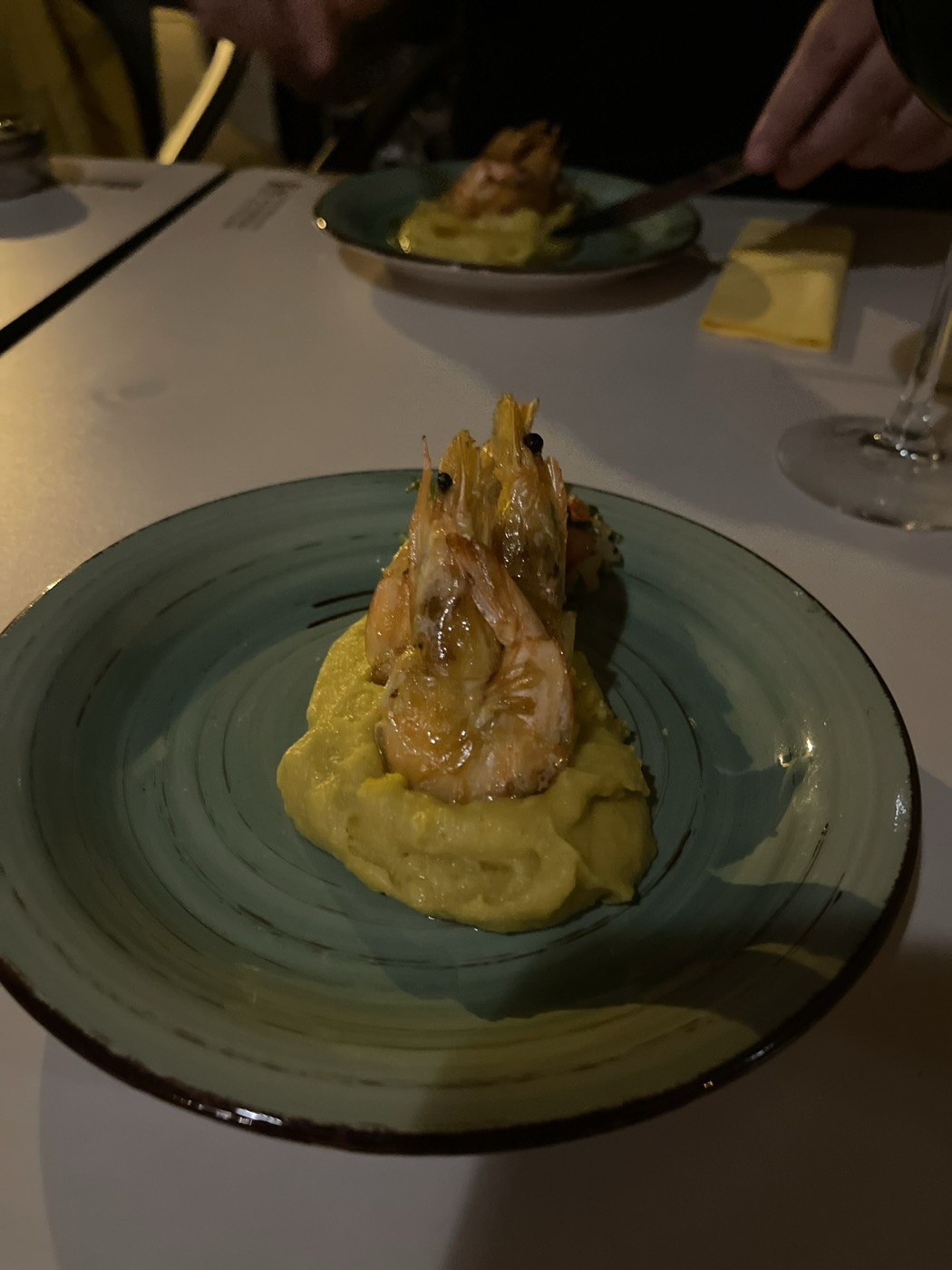 Prawn served over mash on a green plate