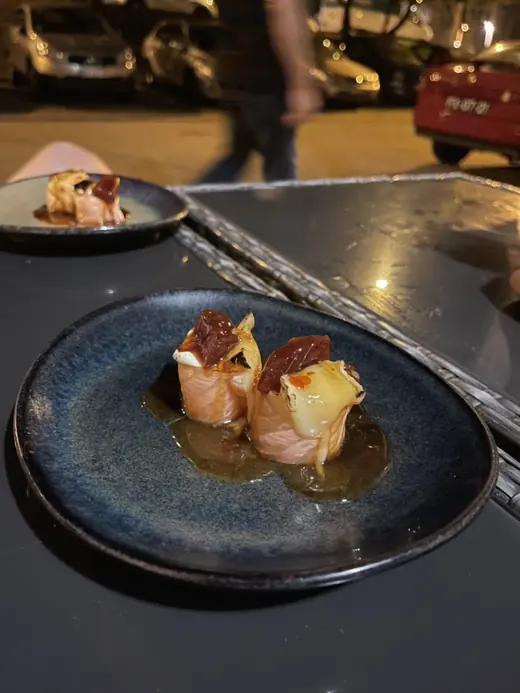 A plated salmon petisco with melted cheese on a blue plate