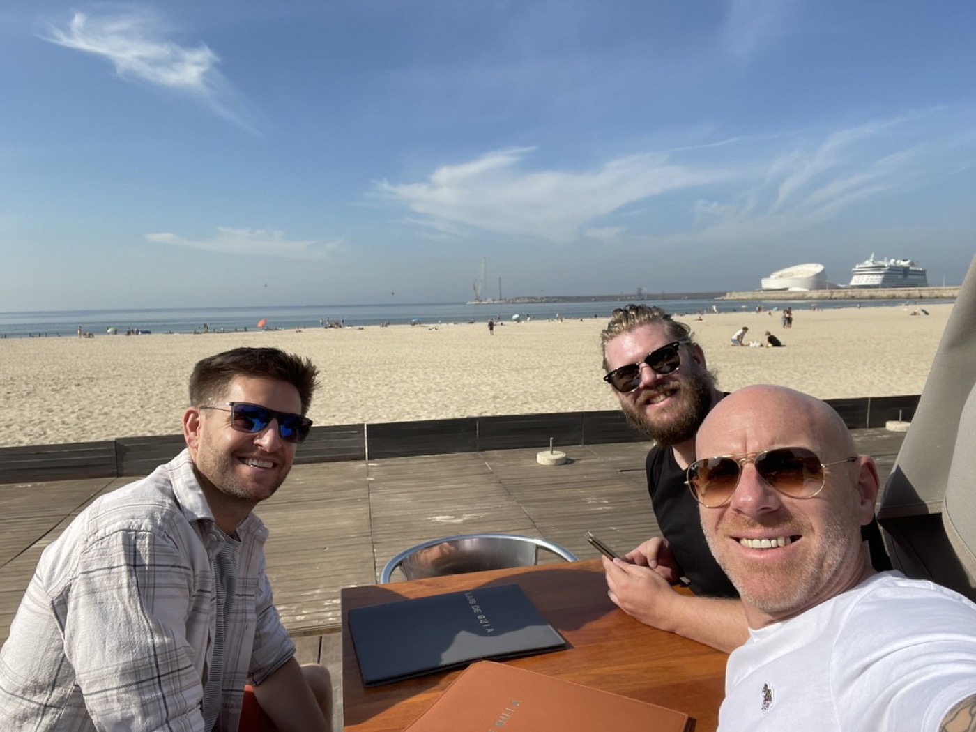 Mat, Dave and Tom at a beachside table, menus out, sunglasses on